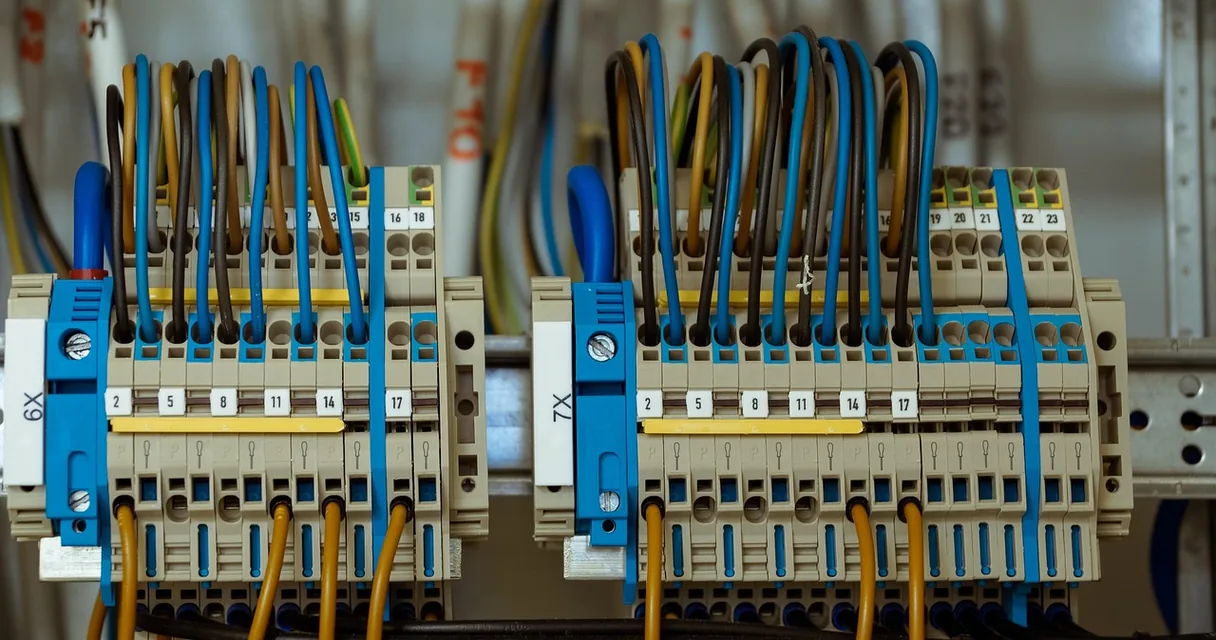 Bornes de conexão com fios azuis, marrons e amarelos dentro de um quadro elétrico